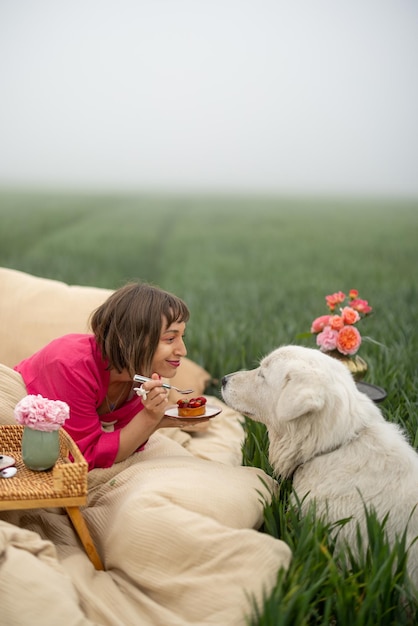 Donna con un cane a letto sul campo verde all'aperto