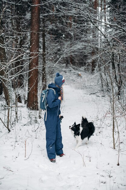 Donna con un cane border collie nella foresta innevata