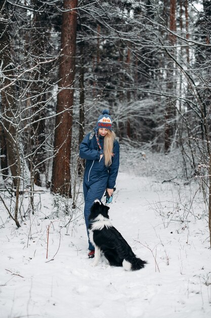 Donna con un cane border collie nella foresta innevata