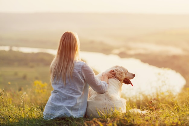 donna con un cane golden retriever che guarda il tramonto