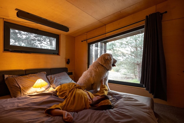 Donna con un cane sdraiato sul letto in cabina di legno sulla natura