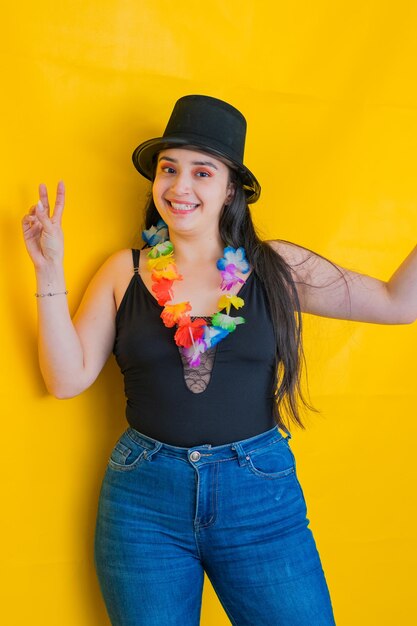 donna con un cappello nero e una collana di fiori che celebra con un grande sorriso sullo sfondo giallo