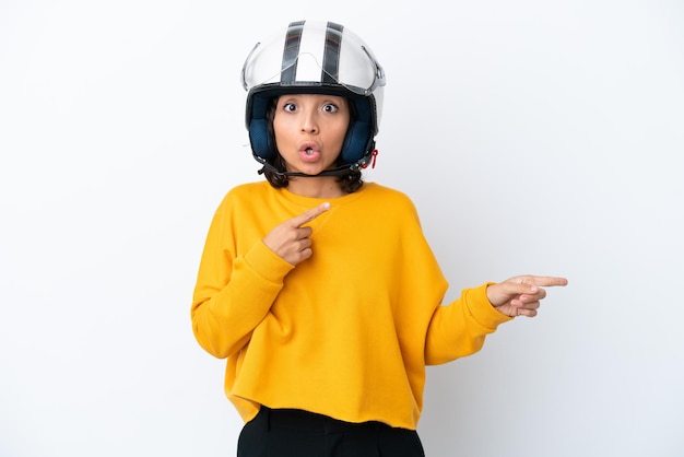 Donna con un casco da motociclista sorpresa e che indica il lato