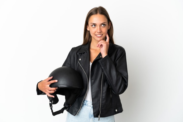 Donna con un casco da motociclista su sfondo bianco isolato pensando a un'idea mentre guarda in alto