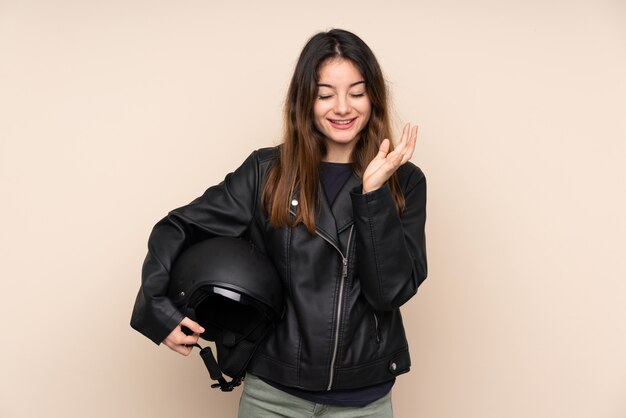 Donna con un casco da motociclista sulla parete beige infelice e frustrata con qualcosa