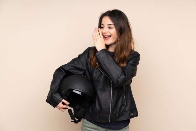 Donna con un casco del motociclo isolato su beige