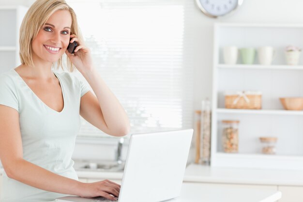 Donna con un computer portatile e un telefono guardando nella telecamera