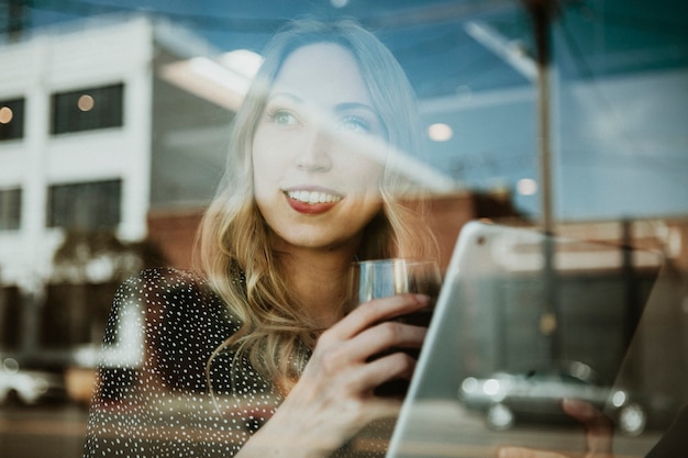 Donna con un drink che utilizza una tavoletta digitale