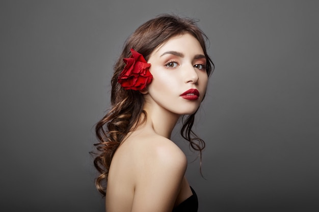 Donna con un grande fiore rosso nei capelli. Capelli castani