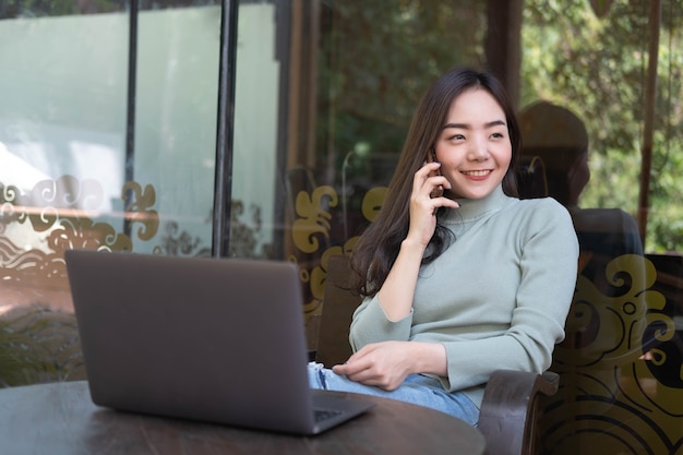 Donna con un sorriso carino che parla con il cellulare mentre riposa al bar Tempo di relax