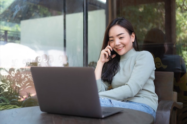 Donna con un sorriso carino che parla con il cellulare mentre riposa al bar Tempo di relax