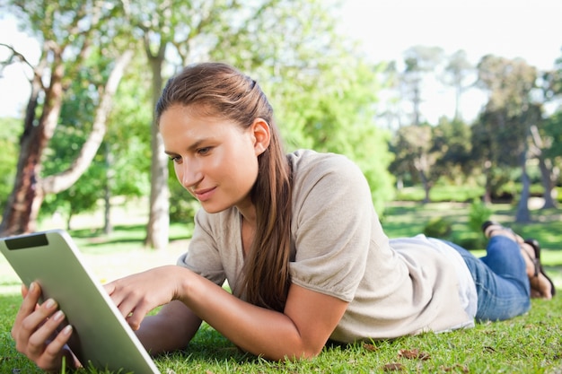 Donna con un tablet PC sdraiato sul prato