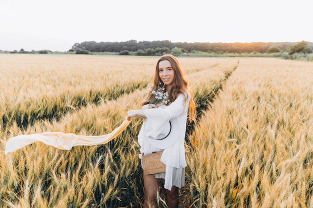 donna con un vestito bianco e un cappello bianco in un campo di grano