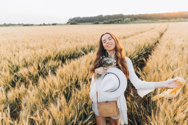 donna con un vestito bianco e un cappello bianco in un campo di grano