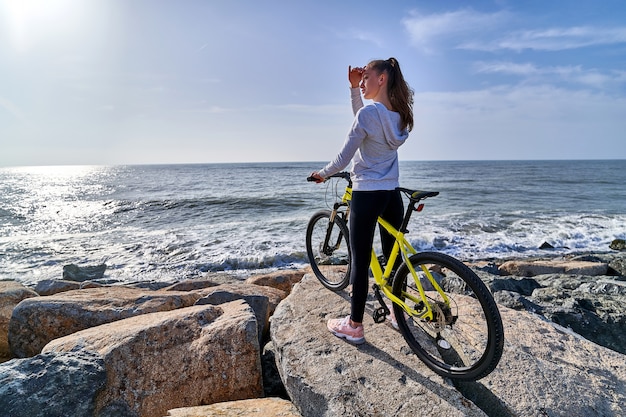 Donna con una bicicletta su una riva