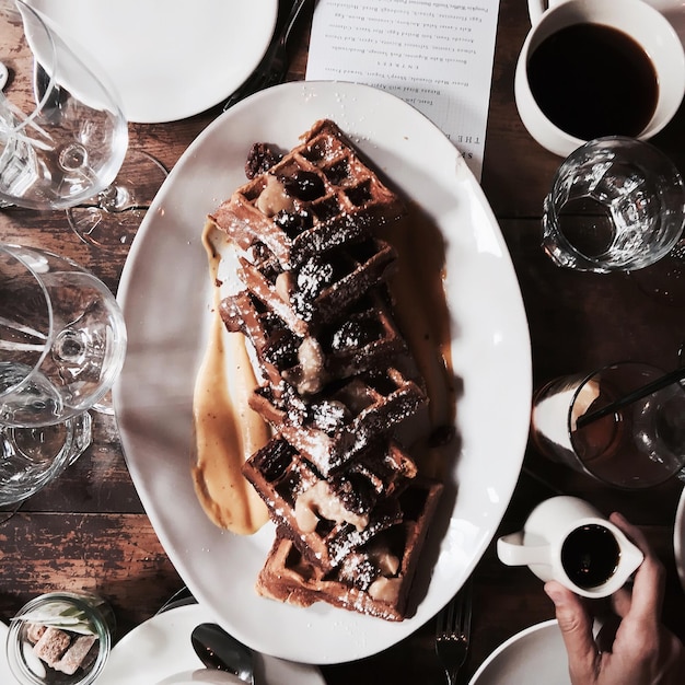 Donna con una brocca con la salsa al cioccolato per i waffle