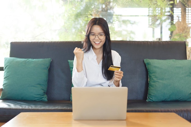 Donna con una carta di credito e che lavora con un laptop