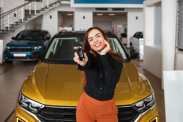 donna con una chiave vicino alla sua nuova auto