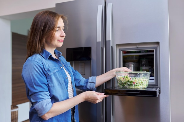 Donna con una ciotola di insalata di verdure dal frigorifero