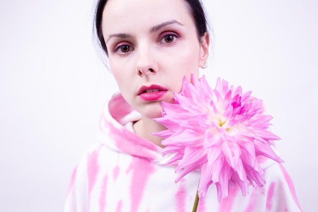 donna con una felpa con cappuccio rosa con in mano un fiore rosa