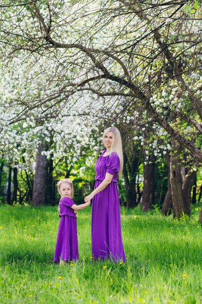 Donna con una figlia piccola che cammina attraverso la fioritura di Apple