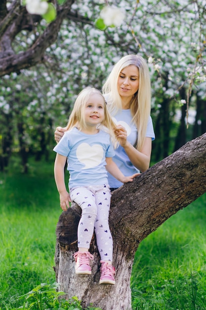 Donna con una figlia piccola che cammina attraverso la fioritura di Apple