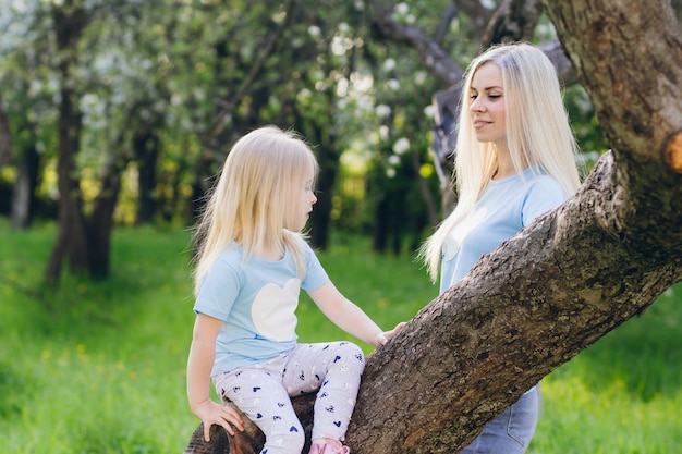 Donna con una figlia piccola che cammina attraverso la fioritura di Apple