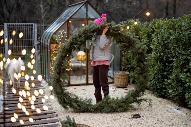 Donna con una grande corona di Natale in cortile