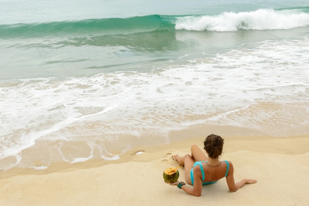 Donna con una noce di cocco sulla spiaggia