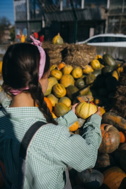 Donna con una piccola zucca tra il raccolto autunnale