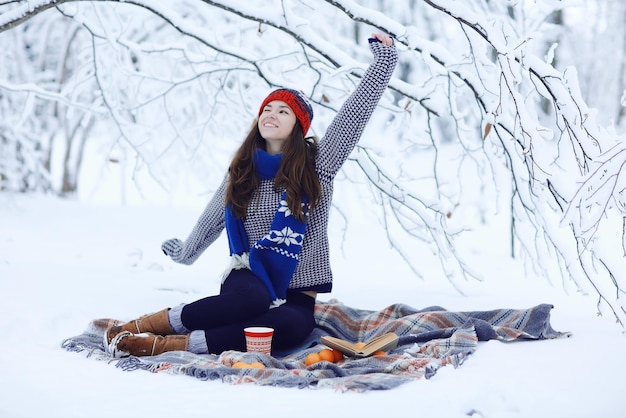 donna con una tazza di bevanda calda nella foresta invernale