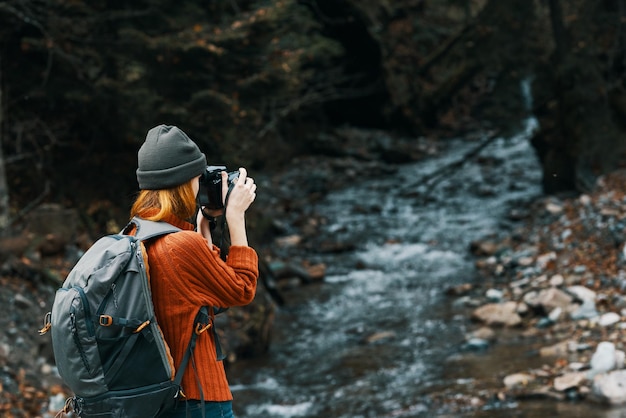 Donna con una telecamera sulla natura nelle montagne vicino al fiume e gli alberi alti paesaggio forestale foto di alta qualità