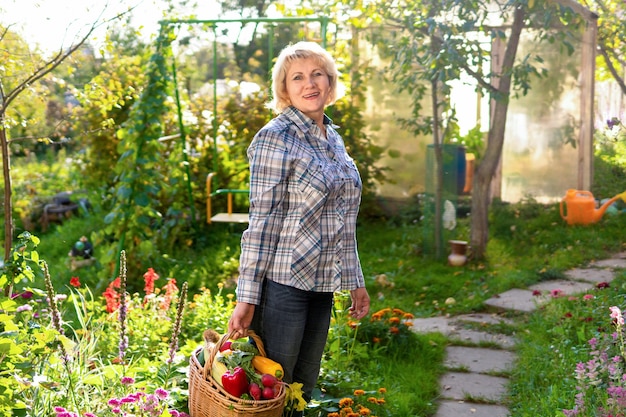 Donna con verdure fresche in un cesto in giardino in autunno