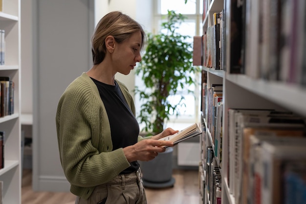 Donna concentrata che trascorre il tempo libero in biblioteca mentre si prepara per l'esame di seconda istruzione superiore