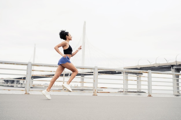 Donna corridore millenaria che corre veloce allenamento sportivo in città Fitness tracker sul braccio