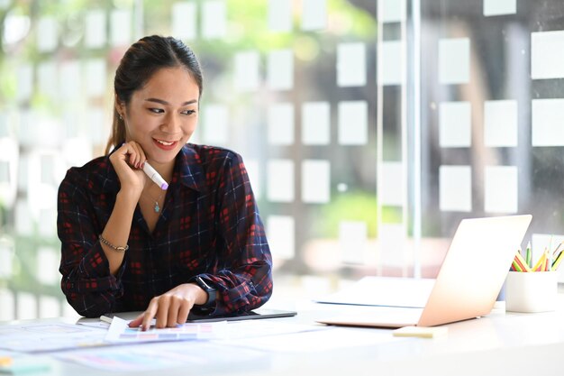 Donna creativa sorridente che lavora per il progetto di progettazione di software applicativo mobile in un ufficio moderno