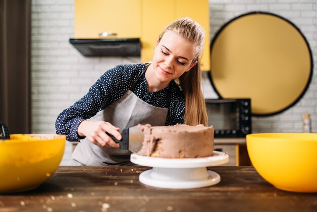 Donna cuoco sbavature torta al forno con crema al cioccolato. Gustosa preparazione di dessert. Cucina casalinga