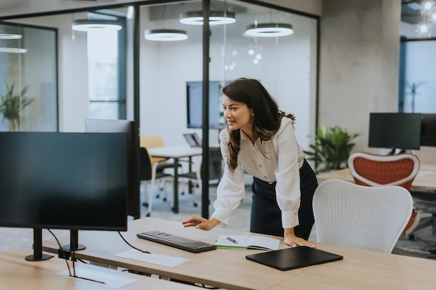 Donna d'affari abbastanza giovane che lavora al computer nell'ufficio moderno