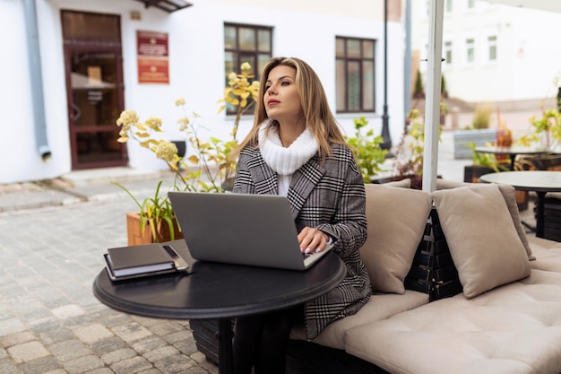Donna d'affari adulta che lavora su un computer portatile a un tavolo in un caffè della città