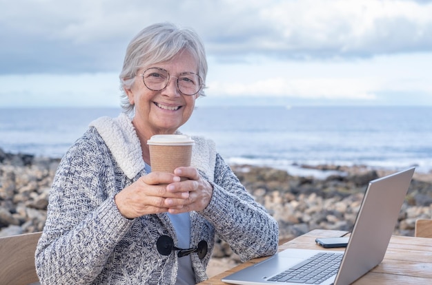 Donna d'affari adulta senior matura attraente felice nel lavoro a distanza sul computer portatile dalla spiaggia