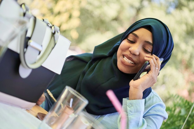 donna d'affari africana che utilizza smart phone indossando abiti islamici tradizionali