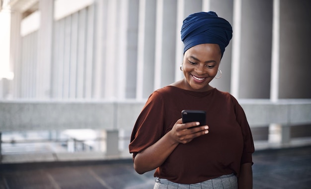 Donna d'affari africana città e sms con telefono sorriso e felicità per contatto chat o notifica e-mail Smartphone imprenditrice femminile e networking con faccia eccitata per la comunicazione