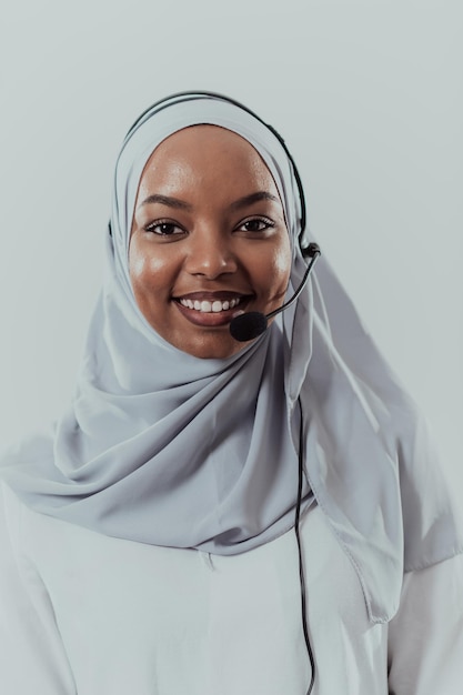 Donna d'affari africana musulmana con sciarpa hijab rappresentante del cliente donna d'affari con auricolare telefonico che aiuta e supporta online con il cliente in un moderno call center luminoso isolato su sfondo bianco