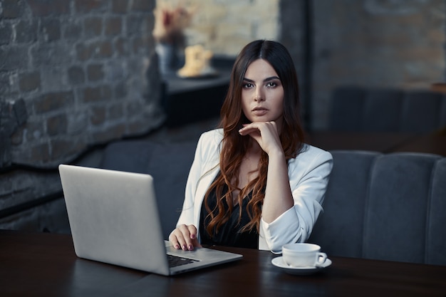 Donna d'affari al lavoro con il computer portatile nella caffetteria