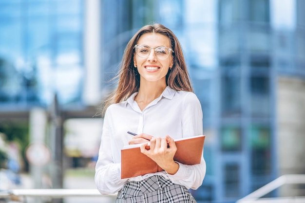 Donna d'affari all'aperto vicino al moderno centro business con notebook.