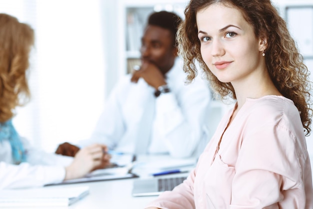 Donna d'affari alla riunione in ufficio, colorata di bianco. Gruppo multietnico di uomini d'affari.