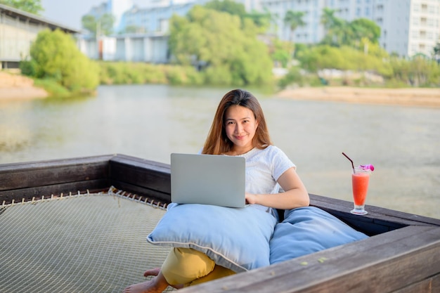 Donna d'affari asiatica che lavora online in spiaggia. Libero professionista che utilizza la tecnologia per lavorare ovunque. Nuovo stile di vita normale dopo il Covid-19.