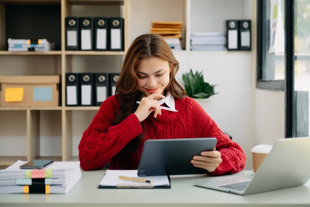 Donna d'affari asiatica che scrive laptop e tablet Posizionato al tavolo dell'ufficioxA