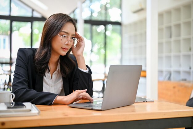 Donna d'affari asiatica stressata che pianifica la sua campagna di progetto lavorando sul suo laptop