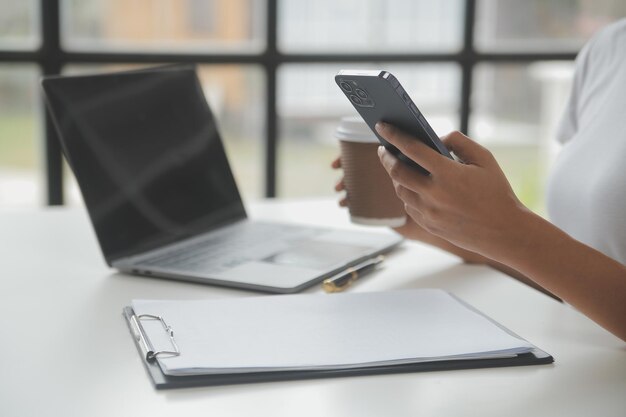 Donna d'affari asiatica Utilizzando il computer portatile e lavorando in ufficio con il documento della calcolatrice sulla scrivania facendo pianificazione analizzando il concetto di analisi finanziaria di investimento del piano aziendale della relazione finanziaria